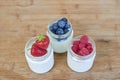 Three glass jars with yogurt and berries on a wooden background Royalty Free Stock Photo