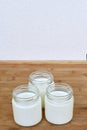 Three glass jars with yogurt on a wooden background. Royalty Free Stock Photo