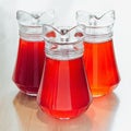 Three glass jugs of fresh red-orange drinks Royalty Free Stock Photo