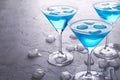 Three glasses of blue cold martini cocktail with ice and clear dew drops on glass on a gray concrete background Royalty Free Stock Photo