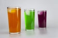 Three glasses with different juices with ice on a white background