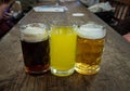 Three glasses of different types of cold tasty beer are in a row on a wooden table Royalty Free Stock Photo