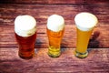 Three glasses of different types of light beer are in a row on a wooden table Royalty Free Stock Photo