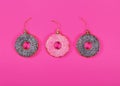 Three glasses donuts on pink background. Christmas toy: chocolate and pink donats. Merry Christmas and Happy New Year concept. Royalty Free Stock Photo