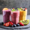 Three glasses of fresh fruit smoothies with berries, kiwi, and mint on dark background Royalty Free Stock Photo