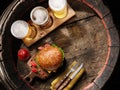 Three glasses of lager beer and hamburger on old wooden barrel. Flat layer