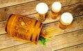 Three glasses of light beer with foam, a wooden barrel, hops and ears of corn on a wooden table Royalty Free Stock Photo