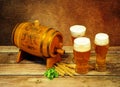 Three glasses of light beer, a wooden barrel, wheat ears and hops on a wooden table Royalty Free Stock Photo