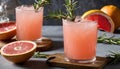 Three glasses of pink grapefruit juice with a sprig of rosemary