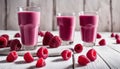 Three glasses of raspberry smoothie with raspberries on the table