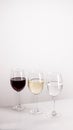 Three glasses of red, white wine and water standing in one line on grey background. Royalty Free Stock Photo