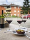 Three glasses of red wine, bottle of wine and chef`s compliment, small plate of paella served on table outdoor terrace Royalty Free Stock Photo