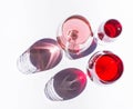 Three glasses of wine: red and pink on white background with sparkling shadows. Royalty Free Stock Photo