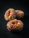 Three glazed Donut with colorful sprinkles isolated on black background. angel view Royalty Free Stock Photo