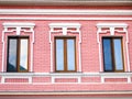 Three glazed windows in brown wooden frames on a pink brick wall Royalty Free Stock Photo