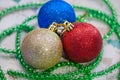 Three glittering Christmas balls golden, blue and red with the green tinsel Royalty Free Stock Photo