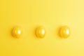 Three glossy painted yellow Easter eggs are lying in row on yellow background. Top view Royalty Free Stock Photo