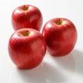 Three glossy red apples are arranged on a white reflective surface Royalty Free Stock Photo