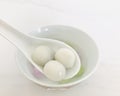 Three glutinous rice balls scooped up from a white bowl on a white spoon. select focus.