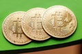Three gold coins bitcoin on a green background