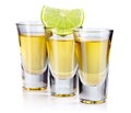 Three gold tequila shots with lime isolated on white