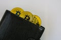 Three golden bitcoins lie in black leather wallet closeup Royalty Free Stock Photo