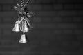 Three golden Christmas bells hanging on a blurred brick wall background, black and white Royalty Free Stock Photo