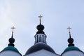 Three golden crosses of a white stone orthodox chirch with black dark domes against a blue cloudy background Royalty Free Stock Photo