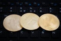 Three golden crypto currency coins on black keyboard