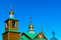 Three Golden domes with a cross of the Orthodox Church made of wood with a green roof and Yakut patterns. Royalty Free Stock Photo