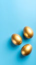 Three golden eggs on a bright blue background, top-down view. Royalty Free Stock Photo