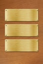 Three golden metal plates over wood texture background