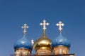 Three golden orthodox bright crosses are on top of blue and golden cupolas on the top of the stone church against blue dark sky Royalty Free Stock Photo