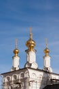 Three golden orthodox bright crosses are on top of golden cupolas on the top of the stone white under construction church against Royalty Free Stock Photo