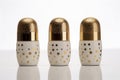 three golden thimbles with white bases, adorned with various sized holes, aligned on a reflective surface