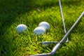 Three golf balls and golf clubs on green Royalty Free Stock Photo