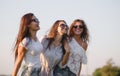 Three gorgeous young women in sunglasses dressed in the beautiful clothes are laughing outdoor on a sunny day. Royalty Free Stock Photo