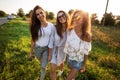 Three gorgeous young women in sunglasses dressed in the beautiful clothes stand in the field and smiling on a sunny day. Royalty Free Stock Photo