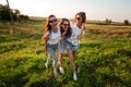 Three gorgeous young women in sunglasses dressed in the beautiful clothes stand in the field and smiling on a sunny day. Royalty Free Stock Photo