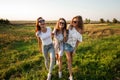 Three gorgeous young women in sunglasses dressed in the beautiful clothes stand in the field and smiling on a sunny day. Royalty Free Stock Photo