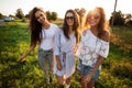 Three gorgeous young women in sunglasses dressed in the beautiful clothes stand in the field and smiling on a sunny day. Royalty Free Stock Photo