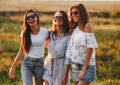 Three gorgeous young women in sunglasses stand in the field and smiling on a sunny day. Royalty Free Stock Photo