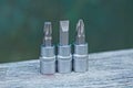 Three gray metal bits for a screwdriver on a gray wooden table Royalty Free Stock Photo