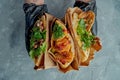 Three Greek pitas sandwich are held in gloved hands. Appetizing pita with meat, chicken and falafel on a gray background. Shawarma Royalty Free Stock Photo