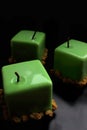 Three green apple shiny glazed cube desserts on black background