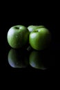 Three green apples on black from side with reflection vertical Royalty Free Stock Photo