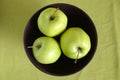 Three green apples inside purple bowl closeup