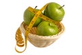 Three green apples wrapped with measuring tape in the wicker basket isolated Royalty Free Stock Photo