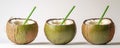 Three green coconuts are positioned on a white background with straws inserted into them Royalty Free Stock Photo