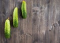 Three green cucumbers lie to the left by a small ladder on a dark gray background Royalty Free Stock Photo